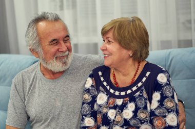 Yakın plan mutlu bayan yaşlı kocayla konuşuyor. Gülümseyen olgun aile çifti evde eğleniyor, sohbet ediyor..