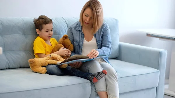 Μητέρα με το γιο να διαβάζει το βιβλίο στον καναπέ στο σπίτι — Φωτογραφία Αρχείου