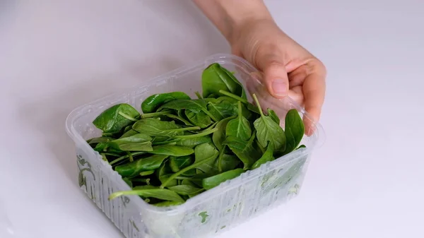 Женщина, использующая пищевую пленку для хранения пищи на белом столе. Ролик прозрачной полиэтиленовой пищевой пленки для упаковки продуктов . — стоковое фото