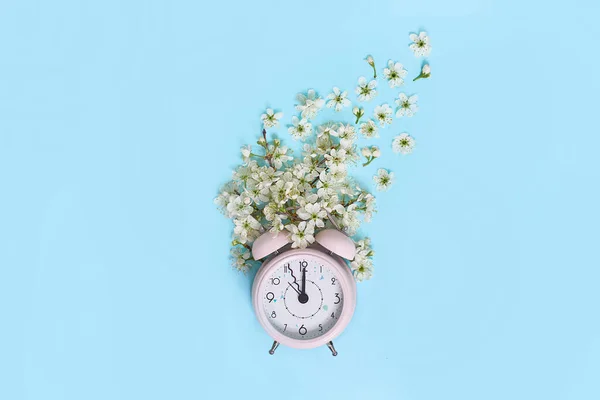 Rosa väckarklocka och fina små vita blommor på blå bakgrund. Högst upp. Dags för kärlek och hälsningar. Vårens tid förändring, vårblommor och väckarklocka. — Stockfoto