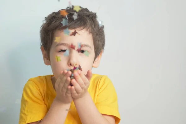 Feliz cumpleaños, niña. Foto de encantador lindo fascinante agradable niño soplando confeti a usted para mostrar su estado de ánimo festivo con expresión emocional de la cara. —  Fotos de Stock