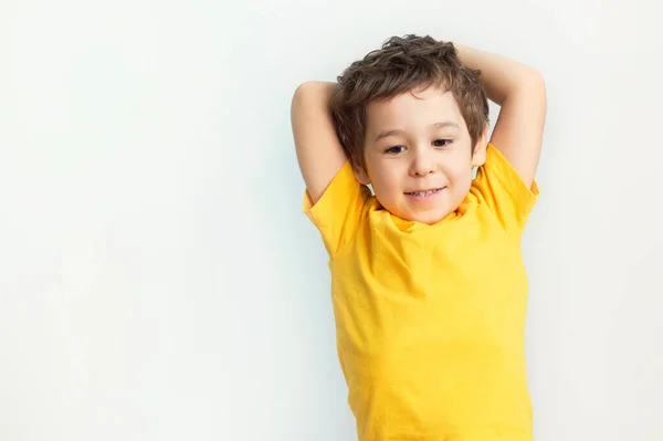 Kleiner Junge mit den Händen hinter dem Kopf. Kind blickt auf Kamera mit Kopierraum. große Träume Lebensstil zu Hause — Stockfoto