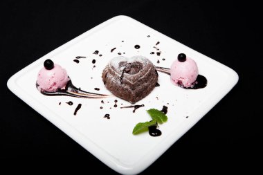 Tatlı fondan çikolata siyah bir zemin üzerine beyaz bir plaka üzerinde dondurma ile. Enfes Fransız çikolata tatlı fondan