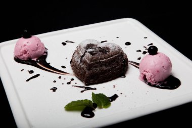 Tatlı fondan çikolata siyah bir zemin üzerine beyaz bir plaka üzerinde dondurma ile. Enfes Fransız çikolata tatlı fondan