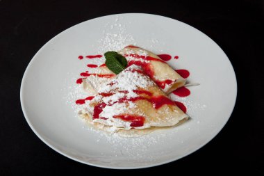 Siyah bir arka plan üzerinde beyaz bir tabakta peynirli gözleme