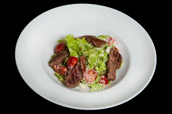 Salada de vitela, salada com grandes fatias de vitela e legumes frescos em uma placa em um fundo preto — Fotografia de Stock