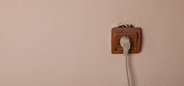 Eski kırık elektrik soketi duvardan düştü. Elektriksel güvenlik ihlali. Metin için yer.