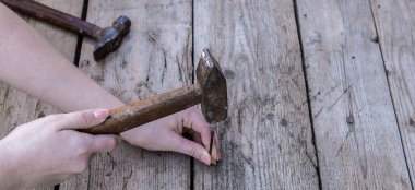 Kadın el tutmak çekiç ve çivi götürmek için bir siyah ahşap masanın üzerinde yatan var. Kopya alanı