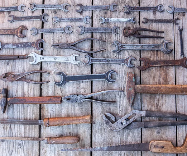 Llave de metal herramientas oxidadas que yacen sobre una mesa de madera negra. Martillo, cincel, sierra, llave de metal. Juego sucio de herramientas de mano sobre un panel de madera fondo vintage con herramientas — Foto de Stock