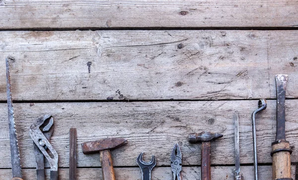 旧的, 生锈的工具躺在黑色的木桌上。锤子, 凿子, 钢锯, 金属扳手。复制空间 — 图库照片