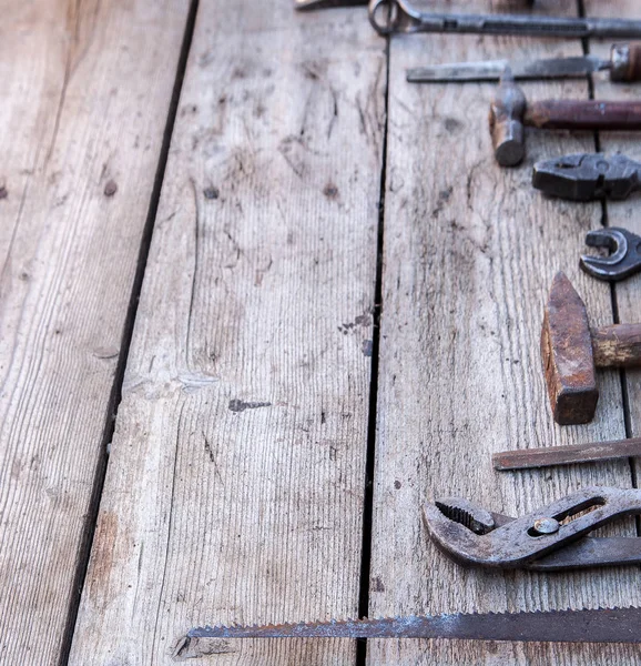 Starý, ošuntělý nástroje ležící na černý dřevěný stůl. Kladivo, dláto, pilku na železo, kovový klíč. Kopírovat prostor — Stock fotografie