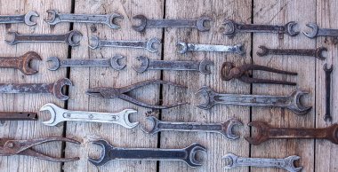 Siyah ahşap masanın üzerinde yatan metal anahtarı paslı araçları. Çekiç, keski, demir testeresi, metal anahtarı. Kirli ahşap panel antika arka plan üzerinde el aletleri ile bir araçlar kümesi