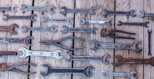 Llave de metal herramientas oxidadas que yacen sobre una mesa de madera negra. Martillo, cincel, sierra, llave de metal. Juego sucio de herramientas de mano sobre un panel de madera fondo vintage con herramientas — Foto de Stock