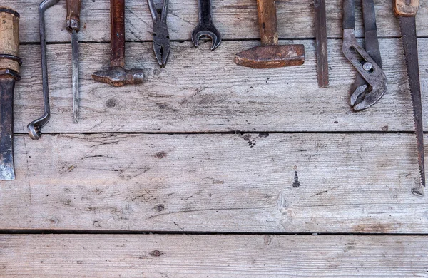 Old, rusty tools lying on a black wooden table. Hammer, chisel, hacksaw, metal wrench.Copy space — Stock Photo, Image