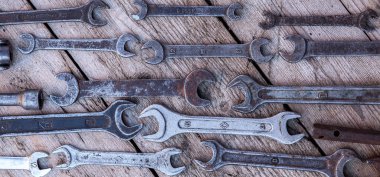 Siyah ahşap masanın üzerinde yatan metal anahtarı paslı araçları. Çekiç, keski, demir testeresi, metal anahtarı. Kirli ahşap panel antika arka plan üzerinde el aletleri ile bir araçlar kümesi.