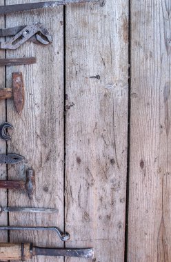 Siyah ahşap masanın üzerinde yatan eski, paslı araçları. Çekiç, keski, demir testeresi, metal anahtarı. Kopya alanı