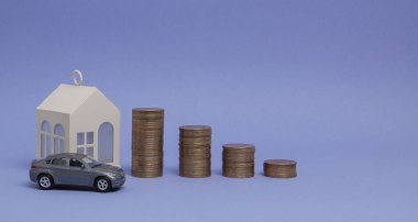 Makine modeli ve mor bir arka plan üzerinde bir çubuk grafik şeklinde paralar ile ev gri. Kredi, tasarruf, satış, kira mülkiyet kavramı