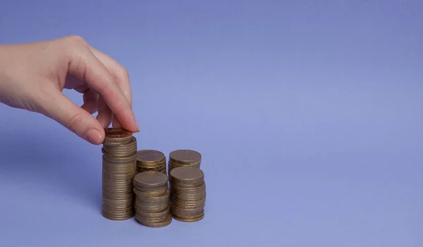 A woman's hand makes coins on a purple background. Concept of lending, savings — Stock Photo, Image