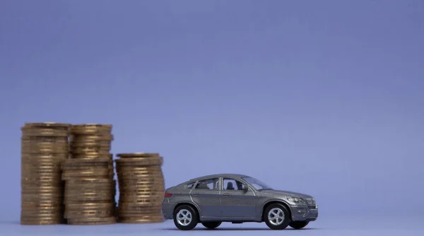 Un modello grigio di una macchina con monete sotto forma di istogramma su sfondo viola. Concetto di prestito, risparmio, assicurazione — Foto Stock