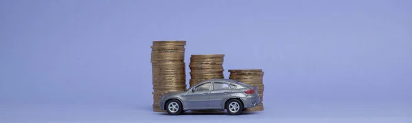 Сіра модель машини з монетами у вигляді гістограми на фіолетовому тлі. Концепція кредитування, заощаджень, страхування — стокове фото