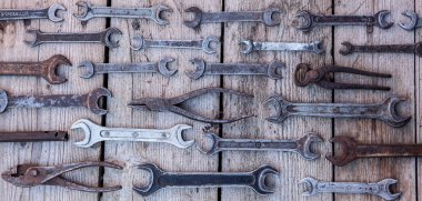 Siyah ahşap masanın üzerinde yatan metal anahtarı paslı araçları. Çekiç, keski, demir testeresi, metal anahtarı. Kirli ahşap panel antika arka plan üzerinde el aletleri ile bir araçlar kümesi.