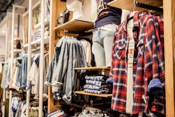 Shorts, skjortor, T-shirts och jacka på butikshyllan. Moderiktiga kläder på hyllorna i butiken. Showcase, försäljning, shopping. Lyx och fashionabla helt ny inredning av trasa butiken — Stockfoto