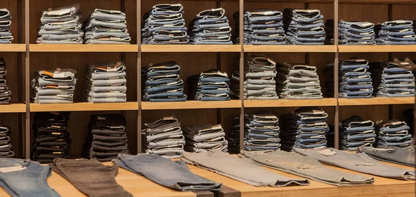 Pantalones vaqueros en el estante de la tienda. Azul jeans denim colección jeans apilados . — Foto de Stock