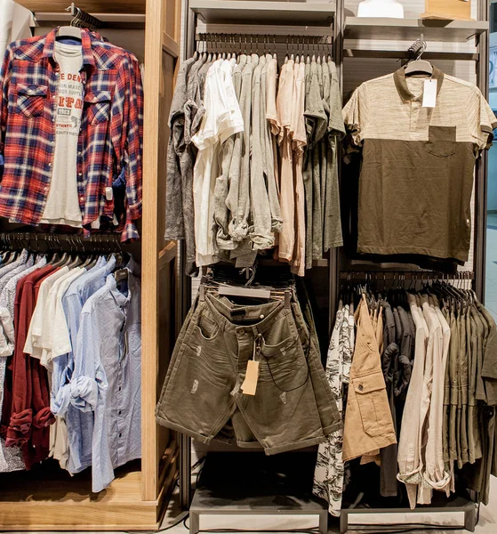 Szorty, koszule, koszulki, a Kurtka na półce sklepowej. Modne ubrania na półkach w sklepie. Prezentacja, sprzedaż, zakupy. Luksusowy i modny nowy wystrój wnętrz sklepu tkaniny — Zdjęcie stockowe