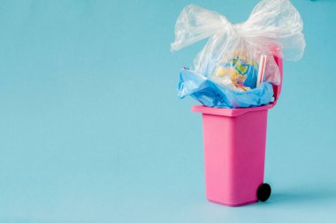 Dünya küresi çöpte yatıyor. Küre bir yığın plast içinde yatıyor.