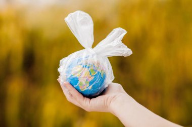 İnsan eli dünyayı plastik bir torba içinde tutuyor. Plastik molozlarla kirlilik kavramı. Sera etkisine bağlı küresel ısınma.