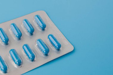 Mavi kapsüller, mavi arka planda haplar. Vitaminler, kadın sağlığı için besin takviyeleri