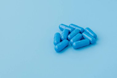 Mavi kapsüller, mavi arka planda haplar. Vitaminler, kadın sağlığı için besin takviyeleri