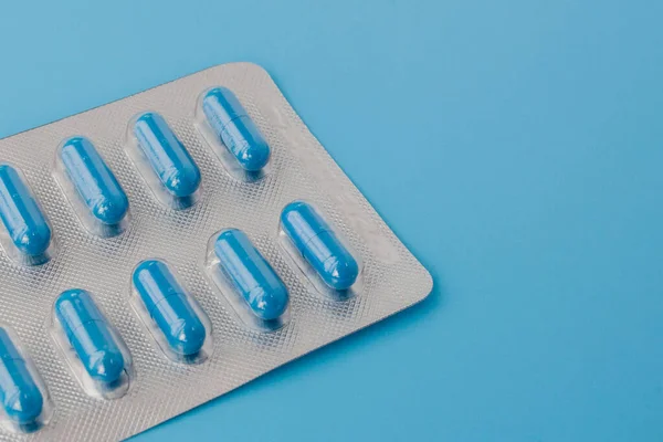 Blå kapslar, piller på blå bakgrund. Vitaminer, näringstillskott för kvinnors hälsa — Stockfoto