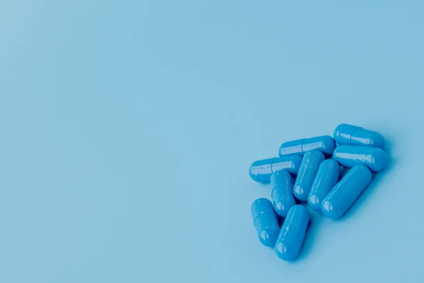 Cápsulas azuis, comprimidos sobre fundo azul. Vitaminas, suplementos nutricionais para a saúde da mulher — Fotografia de Stock