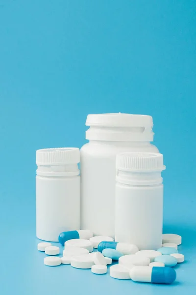 Ассорти лекарственных препаратов таблетки, таблетки и капсулы и бутылки на синем фоне. Копирование текста — стоковое фото