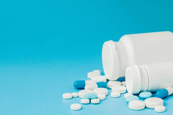 Surtido de píldoras de medicamentos farmacéuticos, tabletas y cápsulas y frasco sobre fondo azul. Copiar espacio para texto — Foto de Stock