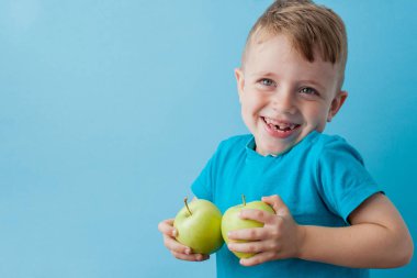 Little Boy mavi arka plan, diyet ve iyi bir sağlık konsepti için egzersiz elinde bir Elma holding