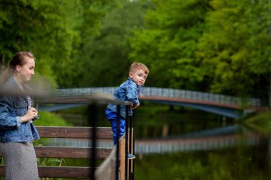 Anne Çocuk suya düşecek yaşıyor. Küçük bir çocuk parkta bir köprüden tırmanıyor. Boğulma tehdidi. Çocuklar için tehlike