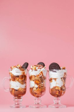 Pembe bsckground, seçici odak ve boş alan üzerinde bisküvi ve krem şanti ile cam tatlı tatlı