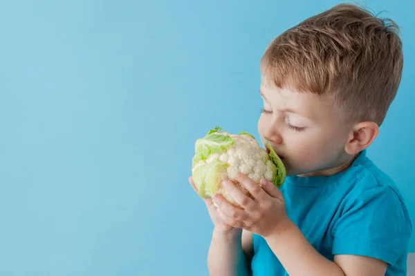 Little Boy Holding Brócoli en sus manos sobre fondo azul, dieta y ejercicio para un buen concepto de salud — Foto de Stock