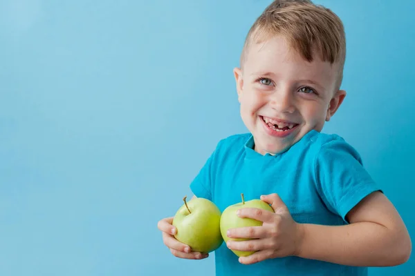 Маленький хлопчик тримає яблука в руках на синьому фоні, дієту і вправи для здорового способу життя — стокове фото