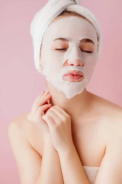Wanita muda yang cantik menerapkan masker jaringan kosmetik pada wajah dengan latar belakang merah muda. Kesehatan dan kecantikan pengobatan dan konsep teknologi — Stok Foto
