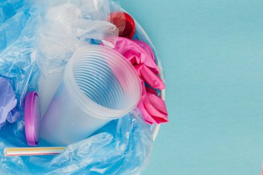 Mavi arkaplanda çeşitli tek kullanımlık plastik atıkların üst görünümü, boşluğu kopyala