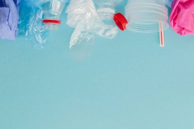 Mavi arkaplanda çeşitli tek kullanımlık plastik atıkların üst görünümü, boşluğu kopyala