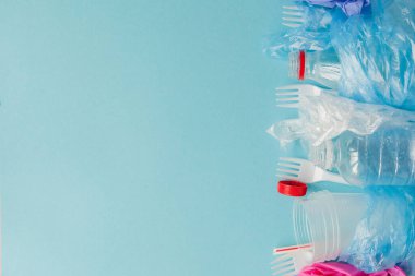 Mavi arkaplanda çeşitli tek kullanımlık plastik atıkların üst görünümü, boşluğu kopyala