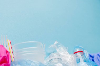 Mavi arkaplanda çeşitli tek kullanımlık plastik atıkların üst görünümü, boşluğu kopyala
