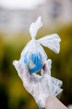 İnsan eli dünyayı plastik bir torba içinde tutuyor. Plastik molozlarla kirlilik kavramı. Sera etkisine bağlı küresel ısınma.