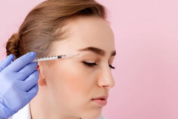 The doctor cosmetologist makes the Botulinotoxin injection procedure for tightening and smoothing wrinkles on the face skin of a beautiful, young woman in a beauty salon.Cosmetology skin care — Stock Photo, Image