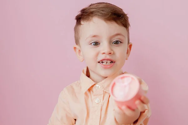 Un niño feliz con un regalo. Foto aislada sobre fondo rosa. El chico sonriente sostiene la caja presente. Concepto de vacaciones y cumpleaños — Foto de Stock