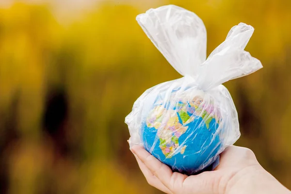 A mão humana segura o planeta Terra num saco de plástico. O conc. — Fotografia de Stock